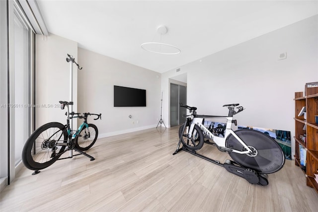 exercise room featuring light wood-type flooring, baseboards, and visible vents
