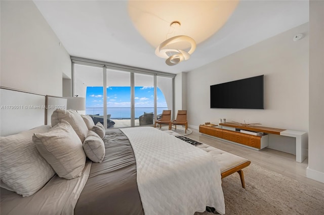 bedroom with baseboards, access to outside, light wood-type flooring, and expansive windows