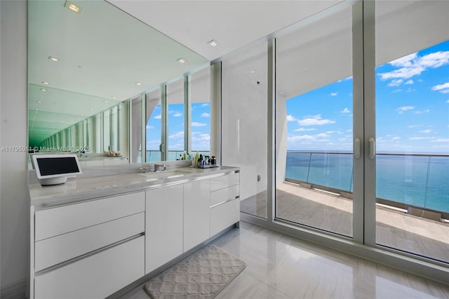 bathroom featuring expansive windows, a water view, and vanity