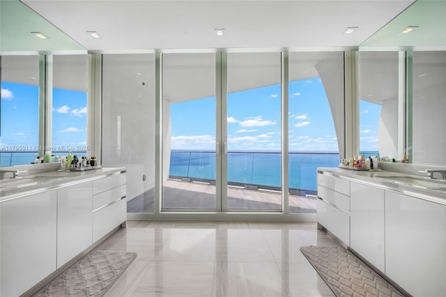bathroom with a sink, two vanities, expansive windows, and a wealth of natural light