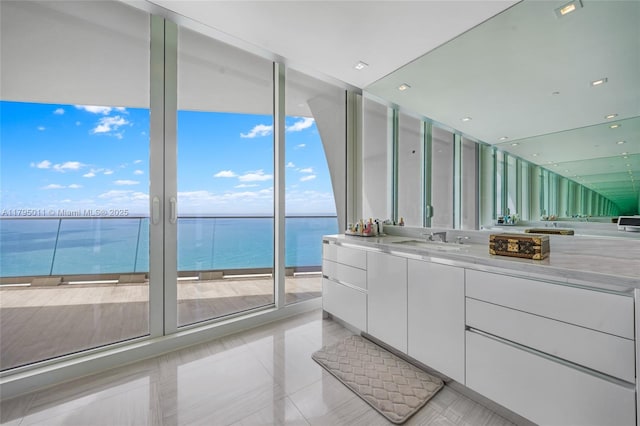 bathroom featuring vanity, a water view, tile patterned floors, and a wall of windows