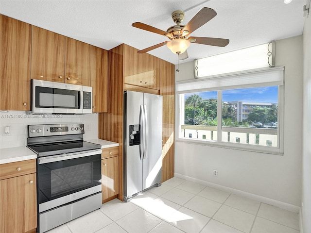 3501 Bimini Ln Unit K2, Coconut Creek, FL 33066 - kitchen featuring appliances with stainless steel finishes, light countertops, brown cabinetry, baseboards, and backsplash