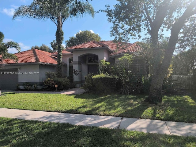 mediterranean / spanish home with stucco siding, a tiled roof, and a front yard