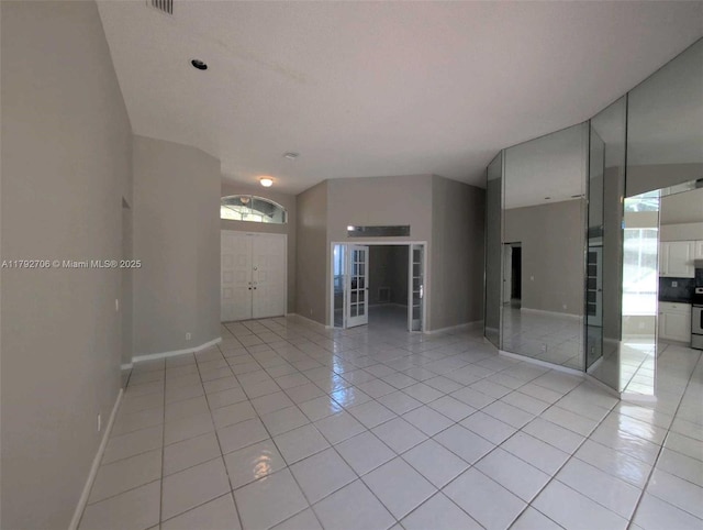 empty room featuring light tile patterned flooring, baseboards, and french doors