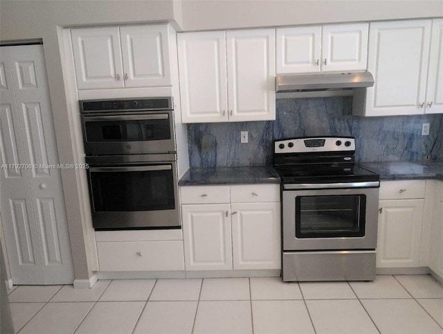 kitchen with under cabinet range hood, stainless steel appliances, dark countertops, and light tile patterned floors