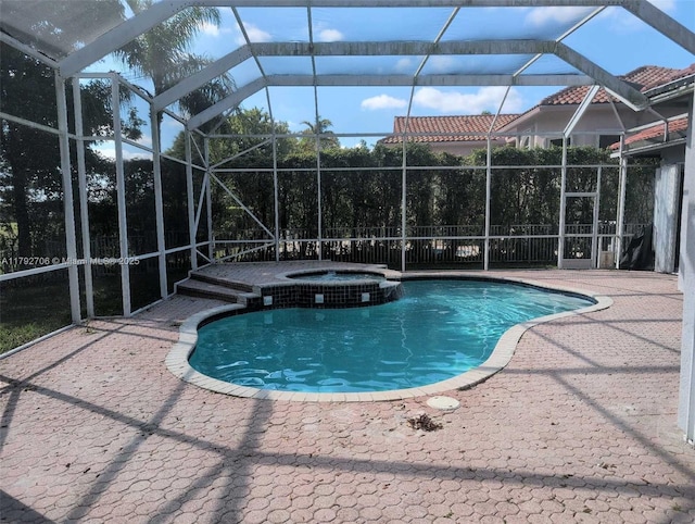 view of swimming pool with glass enclosure, a pool with connected hot tub, and a patio area
