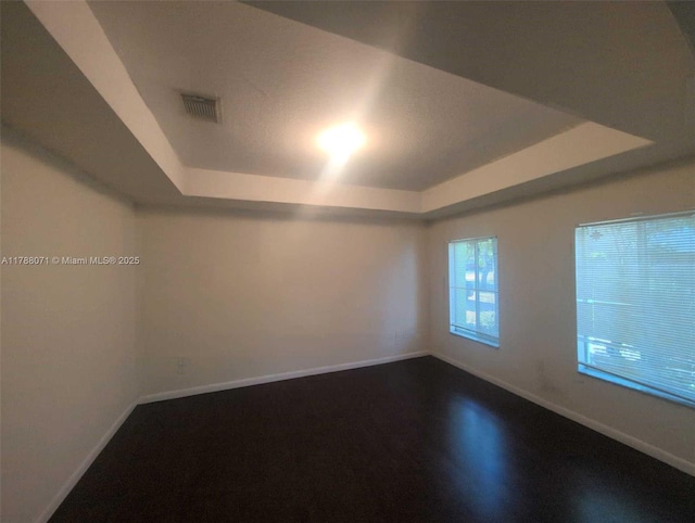 unfurnished room with baseboards, visible vents, and a raised ceiling
