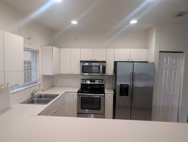 kitchen featuring appliances with stainless steel finishes, a sink, light countertops, recessed lighting, and white cabinetry