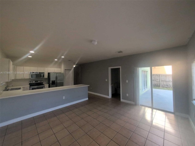 unfurnished living room with tile patterned flooring, a sink, baseboards, and visible vents