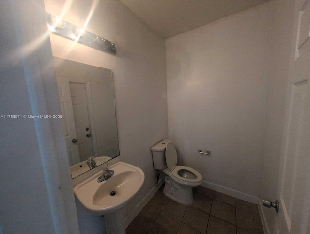 bathroom featuring toilet, a sink, and tile patterned flooring