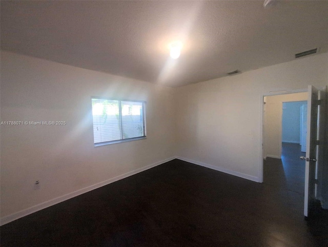 unfurnished room with baseboards and visible vents