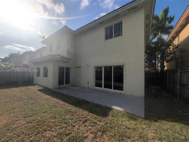 back of property featuring a fenced backyard, stucco siding, a yard, and a patio area