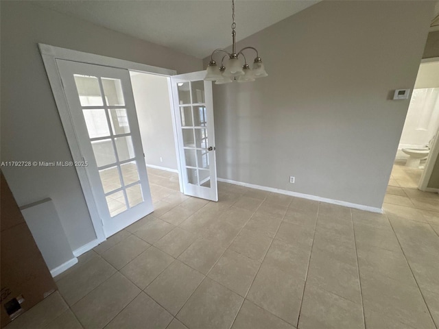 unfurnished dining area featuring tile patterned flooring, baseboards, french doors, and an inviting chandelier