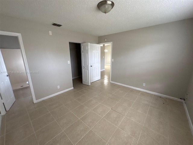 unfurnished bedroom with a textured ceiling, baseboards, visible vents, and a closet