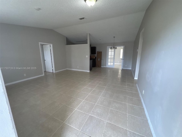 spare room featuring an inviting chandelier, visible vents, baseboards, light tile patterned floors, and vaulted ceiling