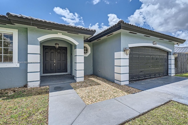 12846 SW 211th Ter, Miami, FL 33177 - property entrance with an attached garage, stucco siding, a tiled roof, and driveway