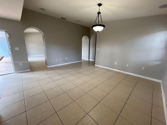 unfurnished room with arched walkways, baseboards, visible vents, and light tile patterned flooring