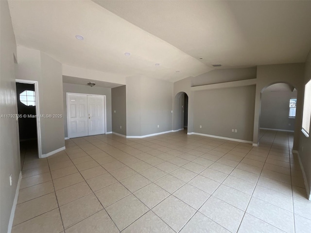spare room with arched walkways and light tile patterned floors