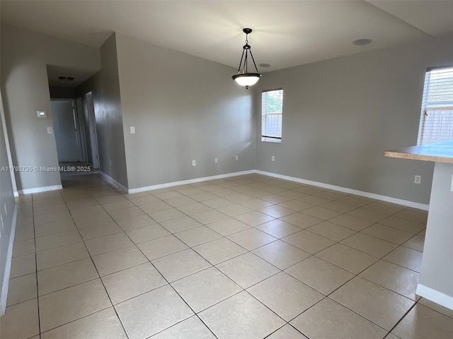 empty room with baseboards, a wealth of natural light, and light tile patterned floors
