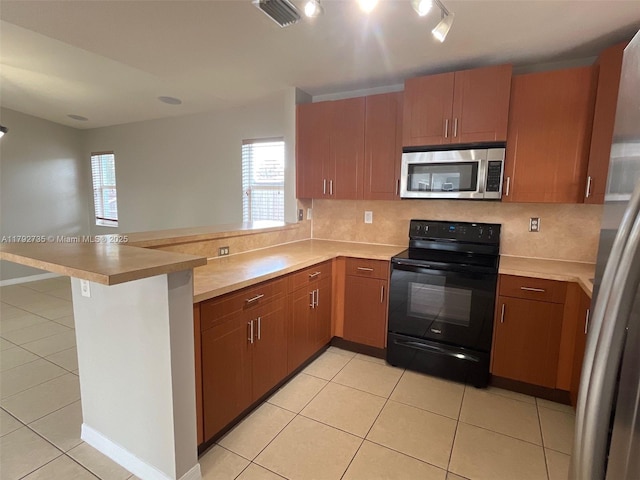 kitchen with stainless steel appliances, a peninsula, a healthy amount of sunlight, tasteful backsplash, and visible vents