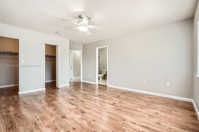12846 SW 211th Ter, Miami, FL 33177 - unfurnished bedroom with wood finished floors, baseboards, ensuite bath, a spacious closet, and a textured ceiling