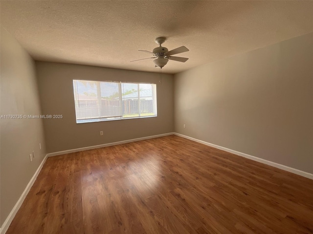 spare room with a textured ceiling, baseboards, a ceiling fan, and wood finished floors