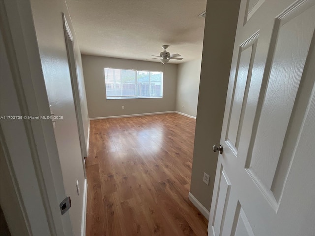 empty room with baseboards, ceiling fan, and wood finished floors