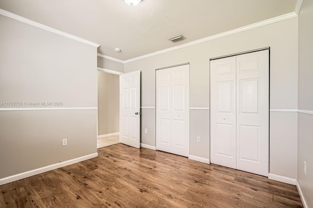 12846 SW 211th Ter, Miami, FL 33177 - unfurnished bedroom featuring ornamental molding, wood finished floors, two closets, and baseboards