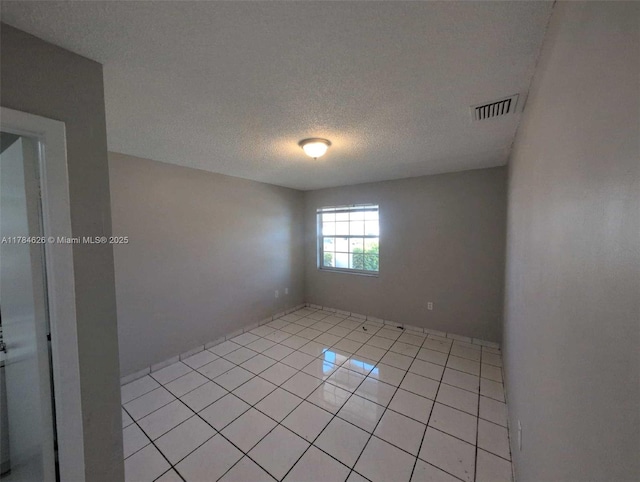 spare room featuring visible vents, a textured ceiling, and light tile patterned floors