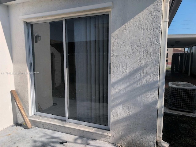 exterior details featuring cooling unit and stucco siding
