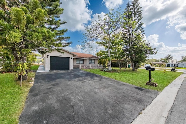 ranch-style house featuring stucco siding, an attached garage, a front yard, and aphalt driveway