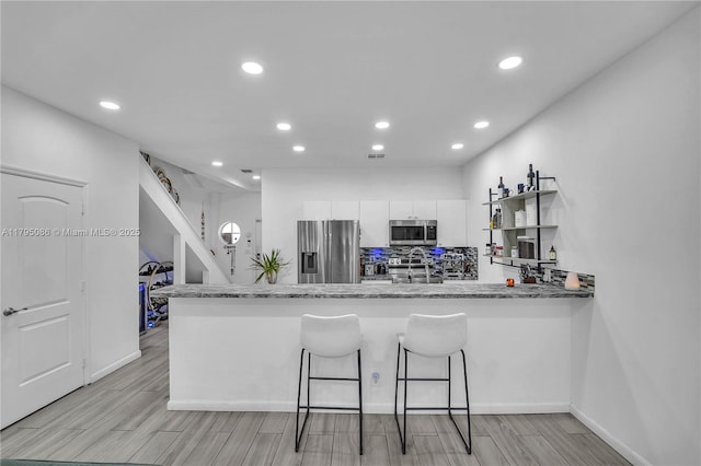 2307 Washington St Unit 5, Hollywood, FL 33020 - kitchen featuring appliances with stainless steel finishes, white cabinetry, a breakfast bar area, recessed lighting, and a peninsula