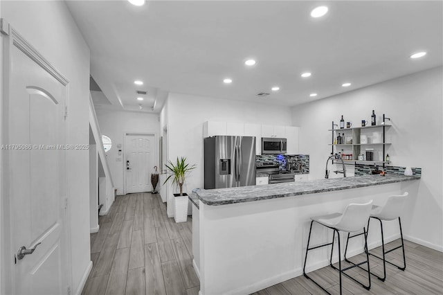 2307 Washington St Unit 5, Hollywood, FL 33020 - kitchen with stainless steel appliances, a peninsula, light wood-type flooring, recessed lighting, and light stone countertops