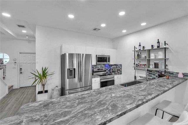 2307 Washington St Unit 5, Hollywood, FL 33020 - kitchen with appliances with stainless steel finishes, backsplash, stone countertops, white cabinetry, and recessed lighting