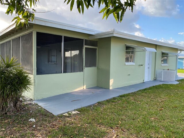 5009 NW 51st Ct, Tamarac, FL 33319 - view of home's exterior featuring a lawn, stucco siding, and a sunroom