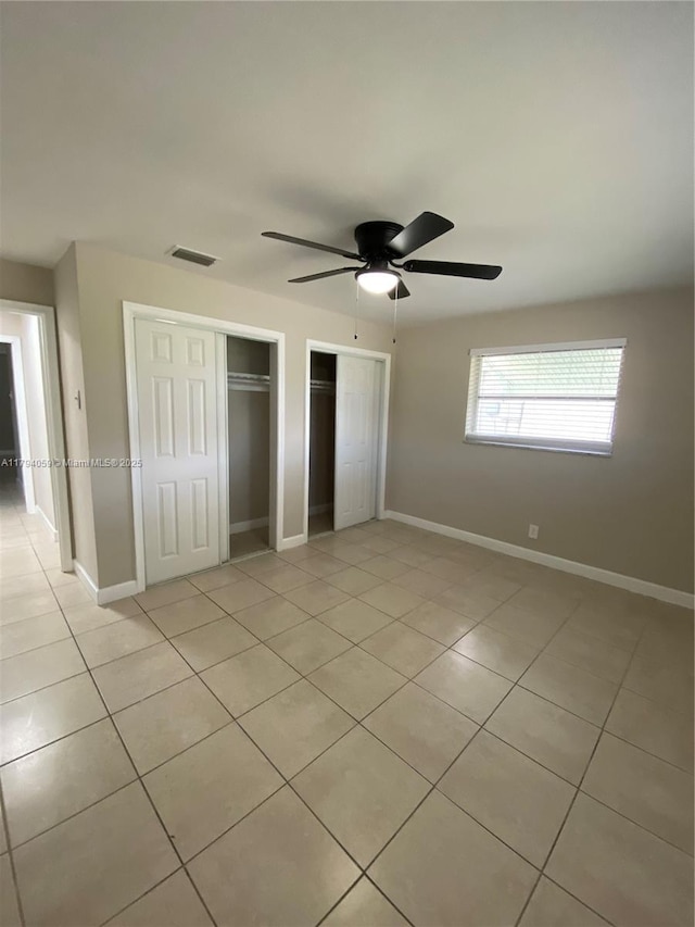 5009 NW 51st Ct, Tamarac, FL 33319 - unfurnished bedroom featuring visible vents, two closets, light tile patterned flooring, baseboards, and ceiling fan
