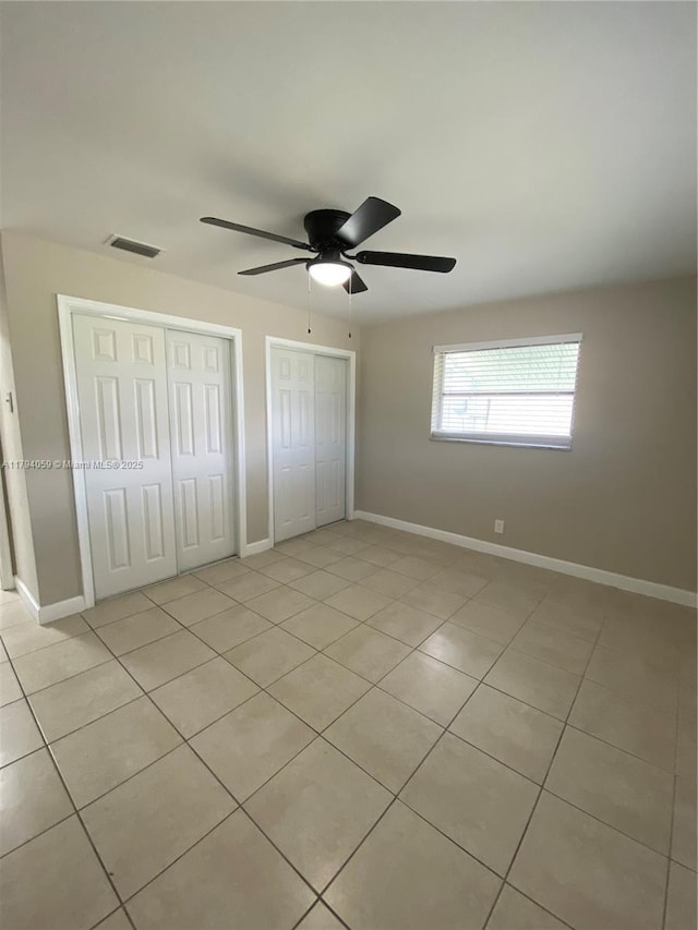 5009 NW 51st Ct, Tamarac, FL 33319 - unfurnished bedroom with ceiling fan, visible vents, light tile patterned floors, baseboards, and multiple closets