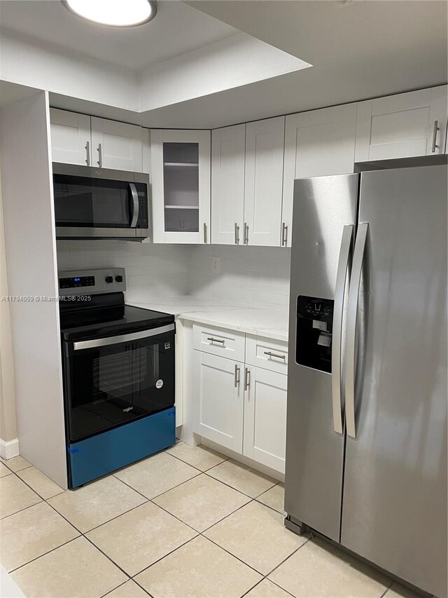 5009 NW 51st Ct, Tamarac, FL 33319 - kitchen with light countertops, appliances with stainless steel finishes, light tile patterned floors, and white cabinetry