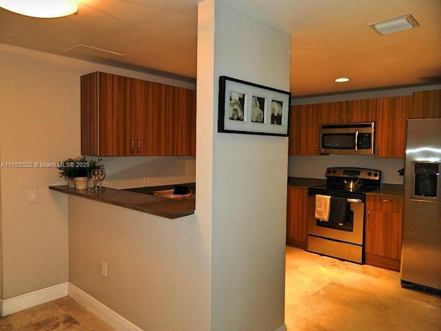 kitchen featuring visible vents, dark countertops, baseboards, brown cabinets, and stainless steel appliances