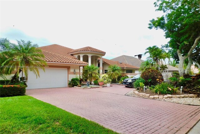 12022 Classic Dr, Coral Springs, FL 33071 - mediterranean / spanish-style home with an attached garage, driveway, stucco siding, and a tile roof