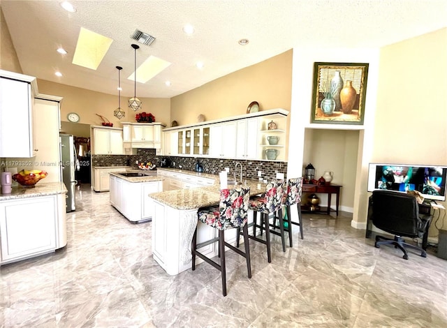 12022 Classic Dr, Coral Springs, FL 33071 - kitchen featuring a skylight, a peninsula, backsplash, light marble finish floors, and freestanding refrigerator