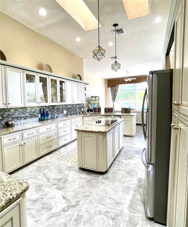 12022 Classic Dr, Coral Springs, FL 33071 - kitchen with freestanding refrigerator, a peninsula, a textured ceiling, a skylight, and tasteful backsplash