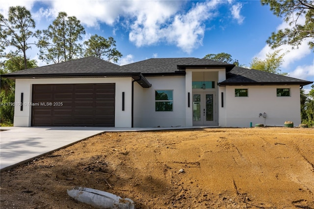 prairie-style house with stucco siding, french doors, a shingled roof, concrete driveway, and an attached garage