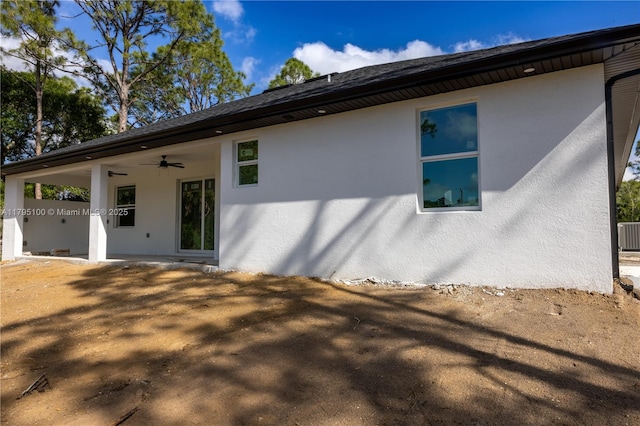 rear view of house with stucco siding, central AC, and ceiling fan