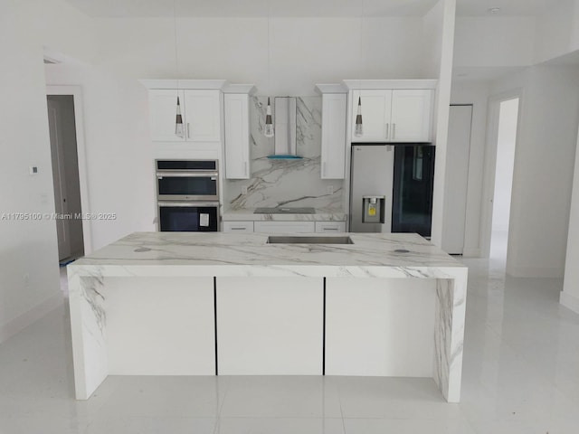 kitchen with white cabinets, appliances with stainless steel finishes, light stone counters, and wall chimney exhaust hood