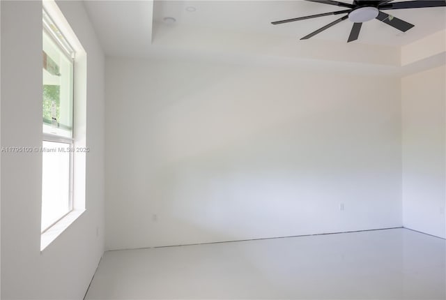 spare room featuring ceiling fan and a raised ceiling