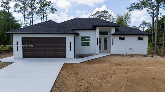 view of front of home with stucco siding, french doors, a shingled roof, and a garage