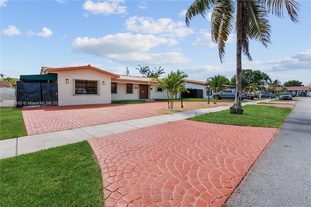 view of front of property featuring decorative driveway, a fenced front yard, stucco siding, and a tiled roof