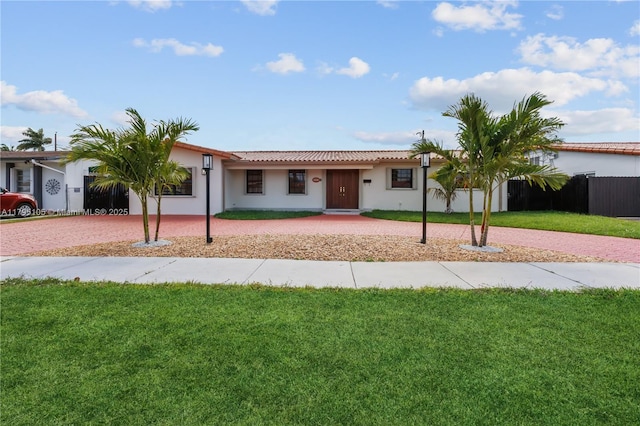 single story home with a tile roof, fence, curved driveway, a front lawn, and stucco siding