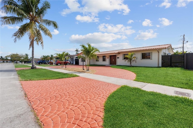 single story home featuring fence, stucco siding, a front yard, decorative driveway, and a tiled roof